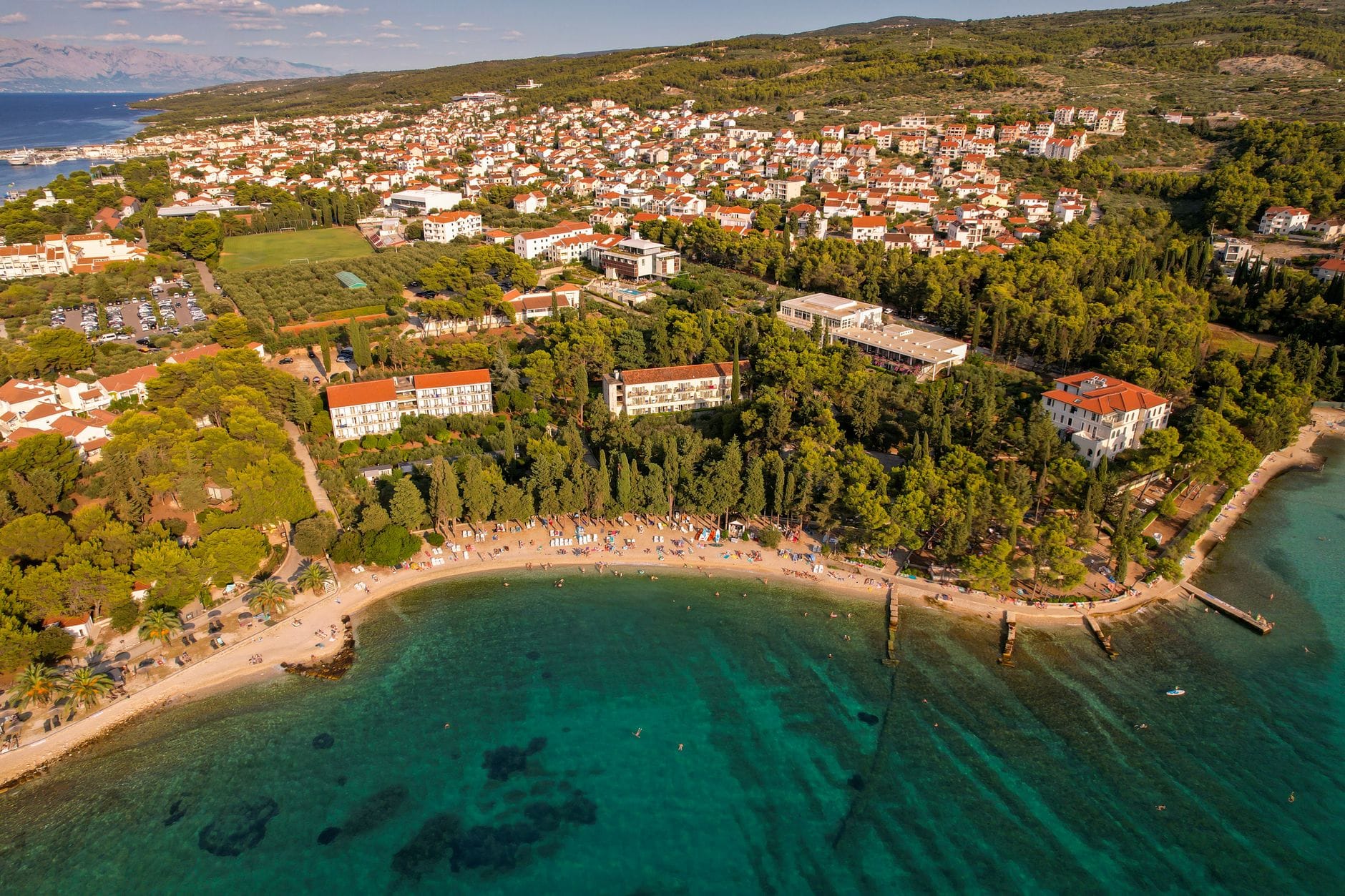 Nadmorska miejscowość w Chorwacji z plażą i zielonym wzgórzem z lotu ptaka